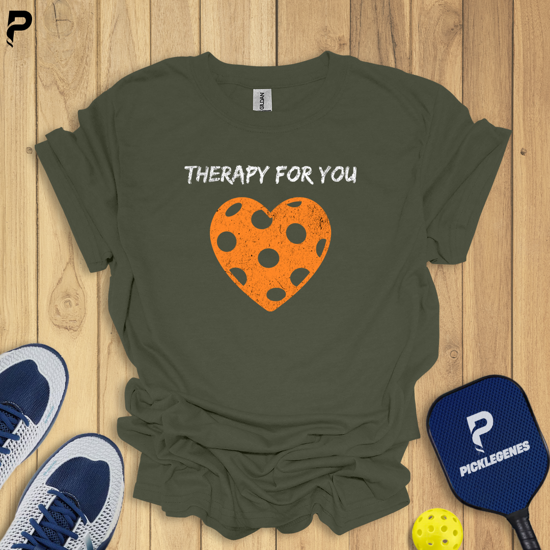 Green t-shirt with a heart design and text on a wooden surface with sports equipment.